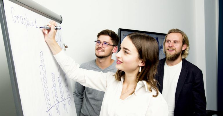 Three professionals collaborating on a business graph presentation in an office setting.